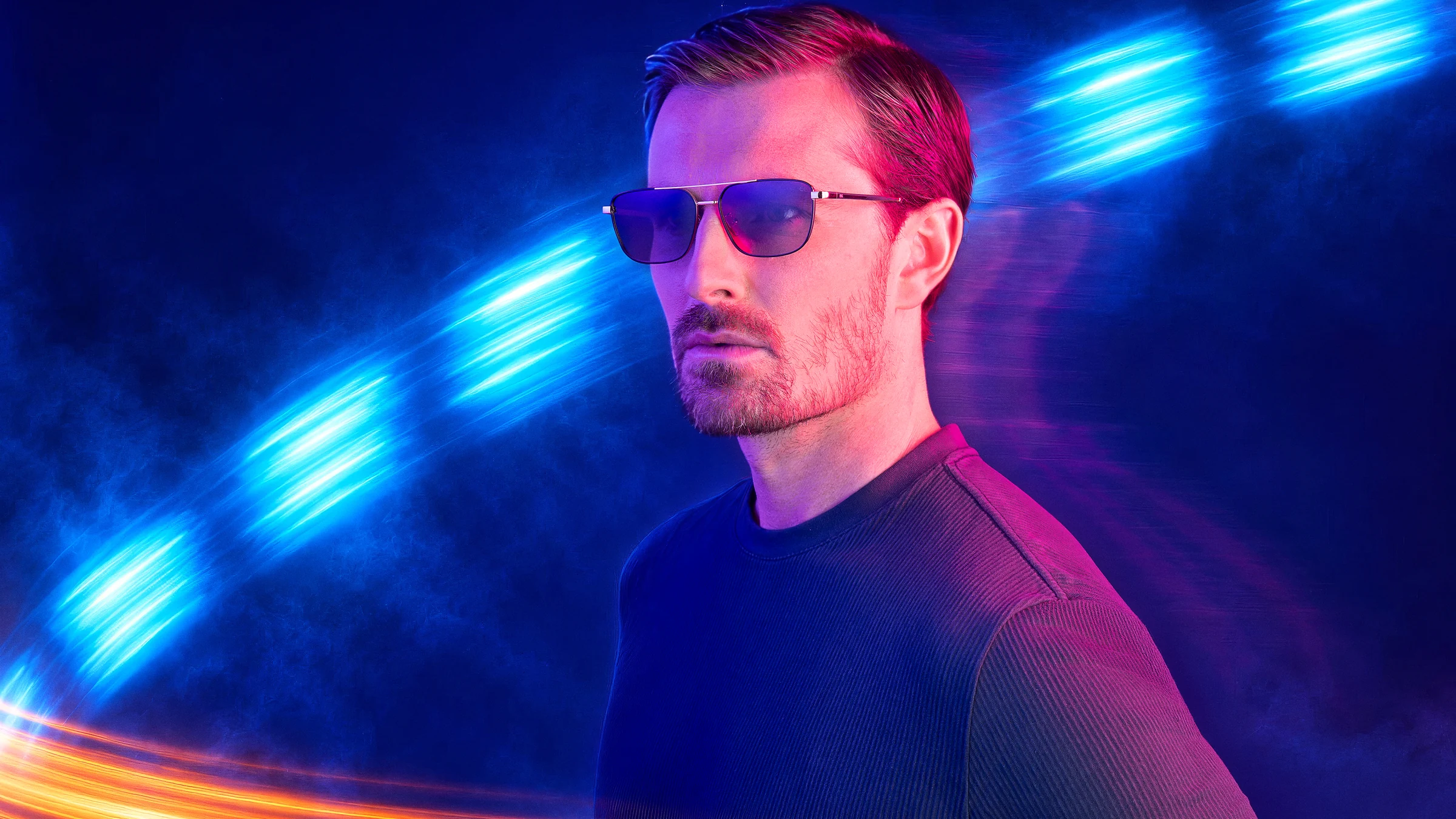 Modelo usando óculos da nova coleção Empório Glasses em cenário com luzes neon azuis e laranjas